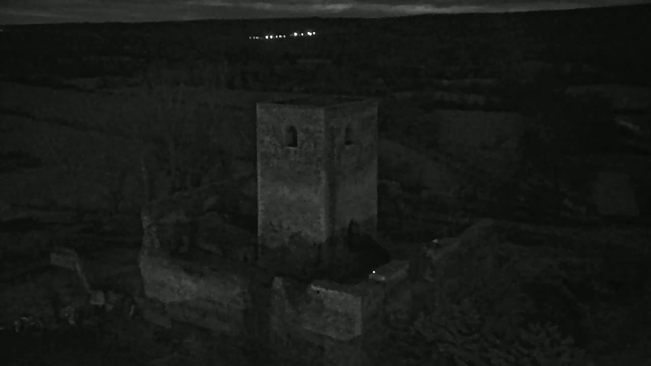 A stone tower, part of a larger ruined structure, stands under a dark night sky.