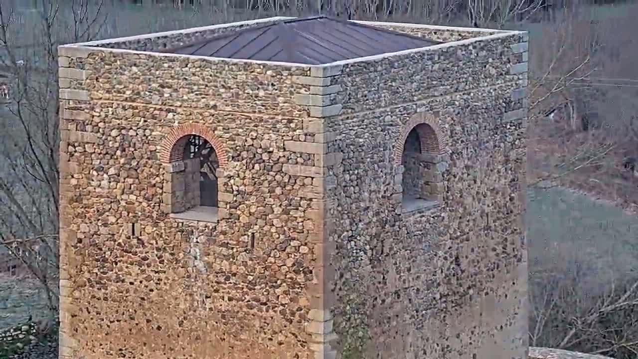 A stone tower with a metal roof stands overlooking a bare winter landscape.