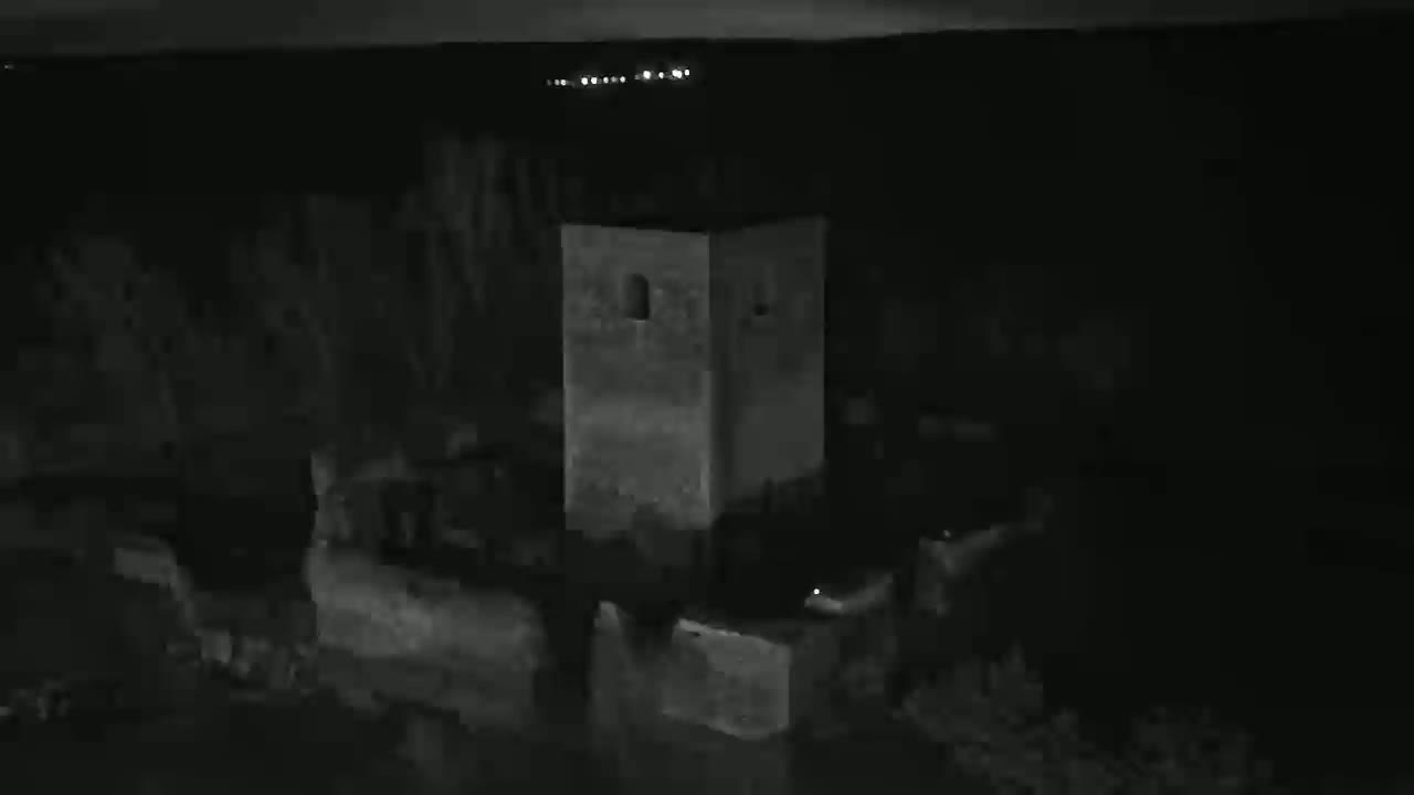 A dark, nighttime view shows a stone tower and surrounding ruins.