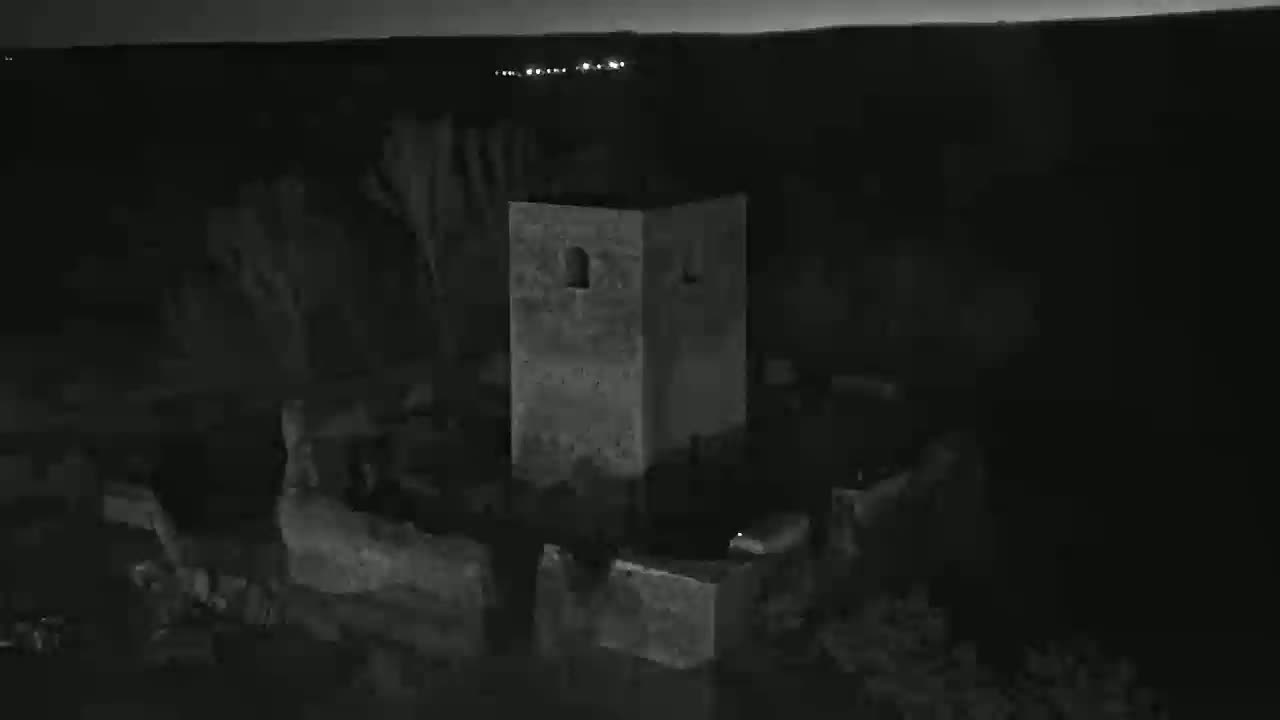 A stone tower stands in the darkness of night, under a clear, dark sky.