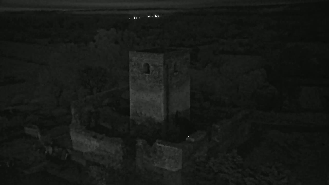 A stone tower and surrounding ruins are visible at night under a dark sky.