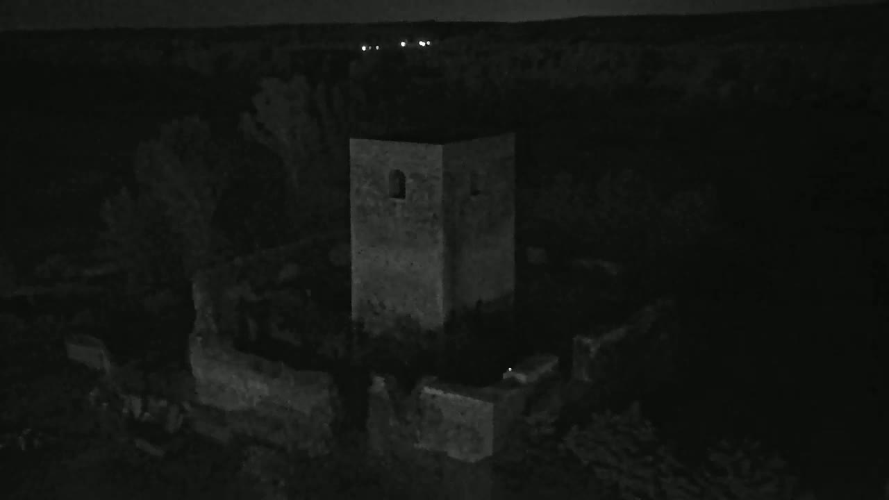 A stone tower and surrounding ruins are visible at night under a dark sky.