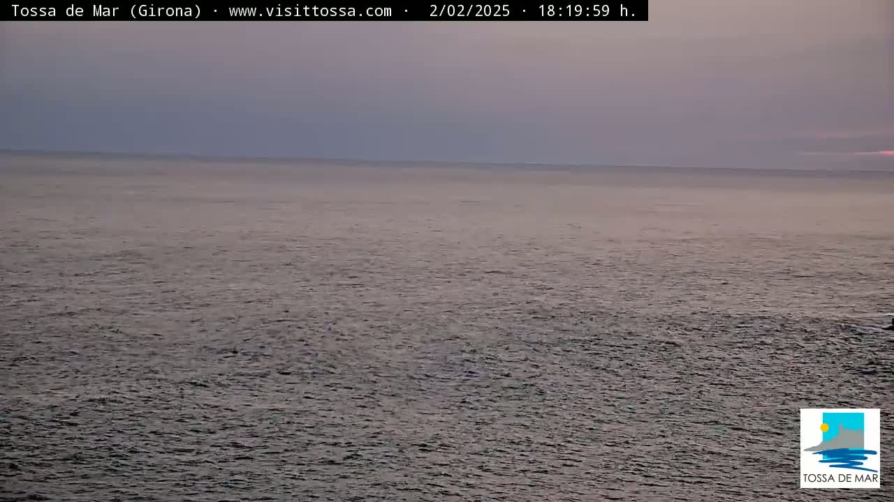 A calm, dark-grey sea stretches to a dusky purple horizon under a mostly cloudy sky.