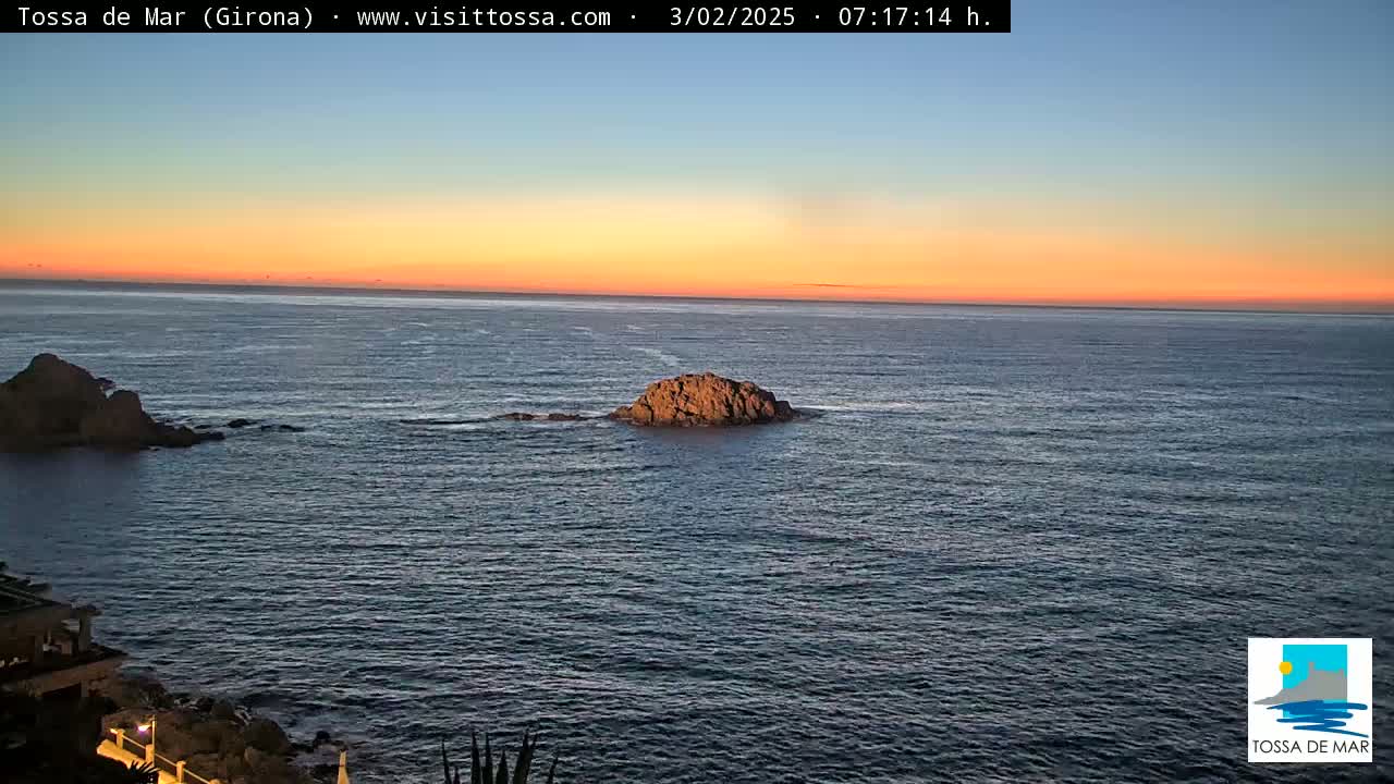 A rocky outcrop sits in a calm sea under a sunset sky.