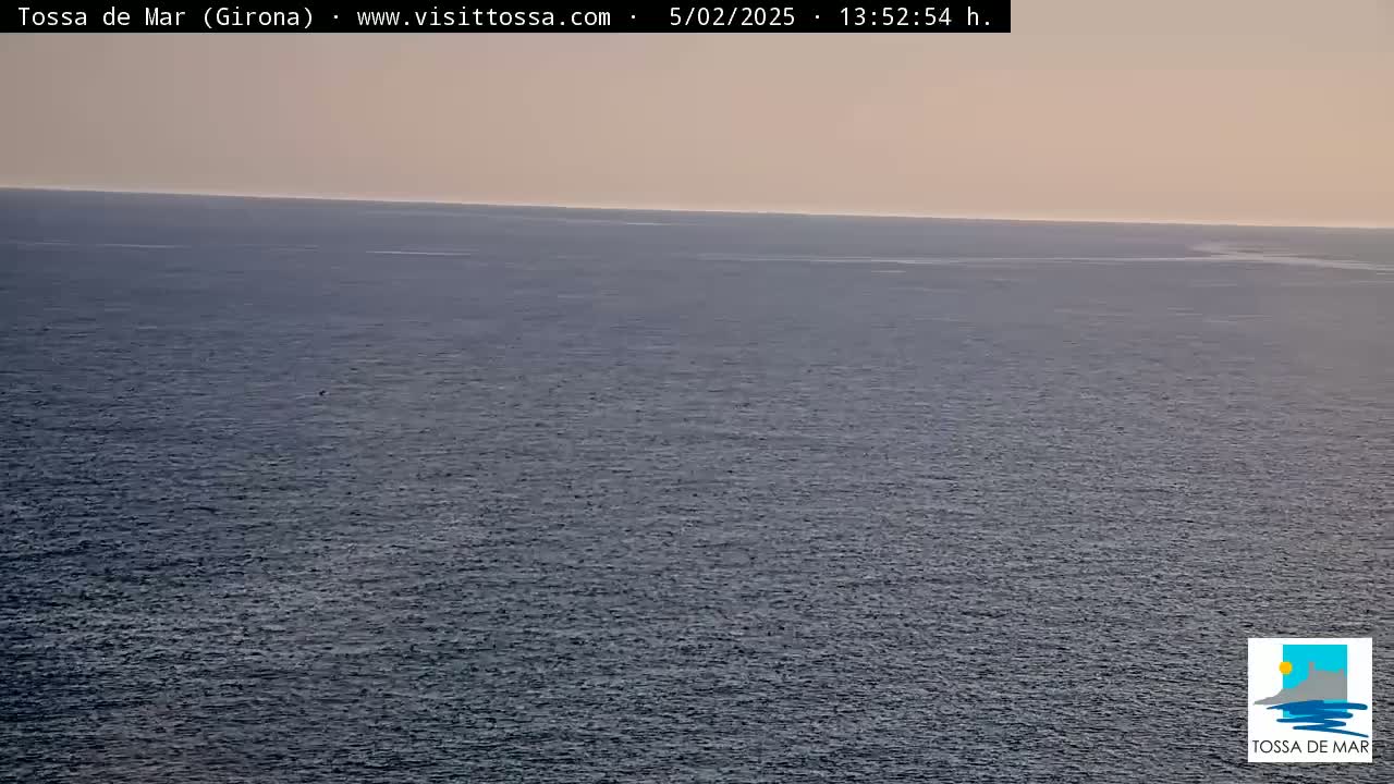 A wide, expansive view of a calm, dark-blue ocean under a pale, hazy sky.