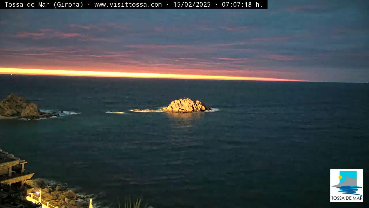 A calm, dark ocean with a rocky outcrop is seen at sunrise, under a sky transitioning from deep purple to orange.