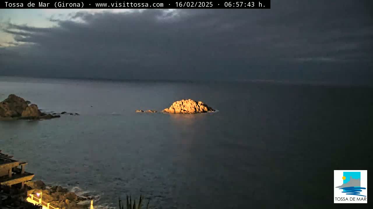 A rocky outcrop is visible in a dark, calm sea under a cloudy sky.