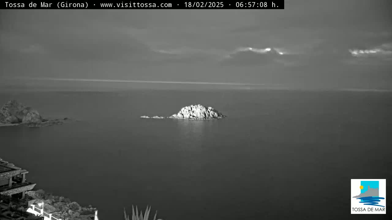 A rocky islet sits in a calm, gray sea under an overcast sky.