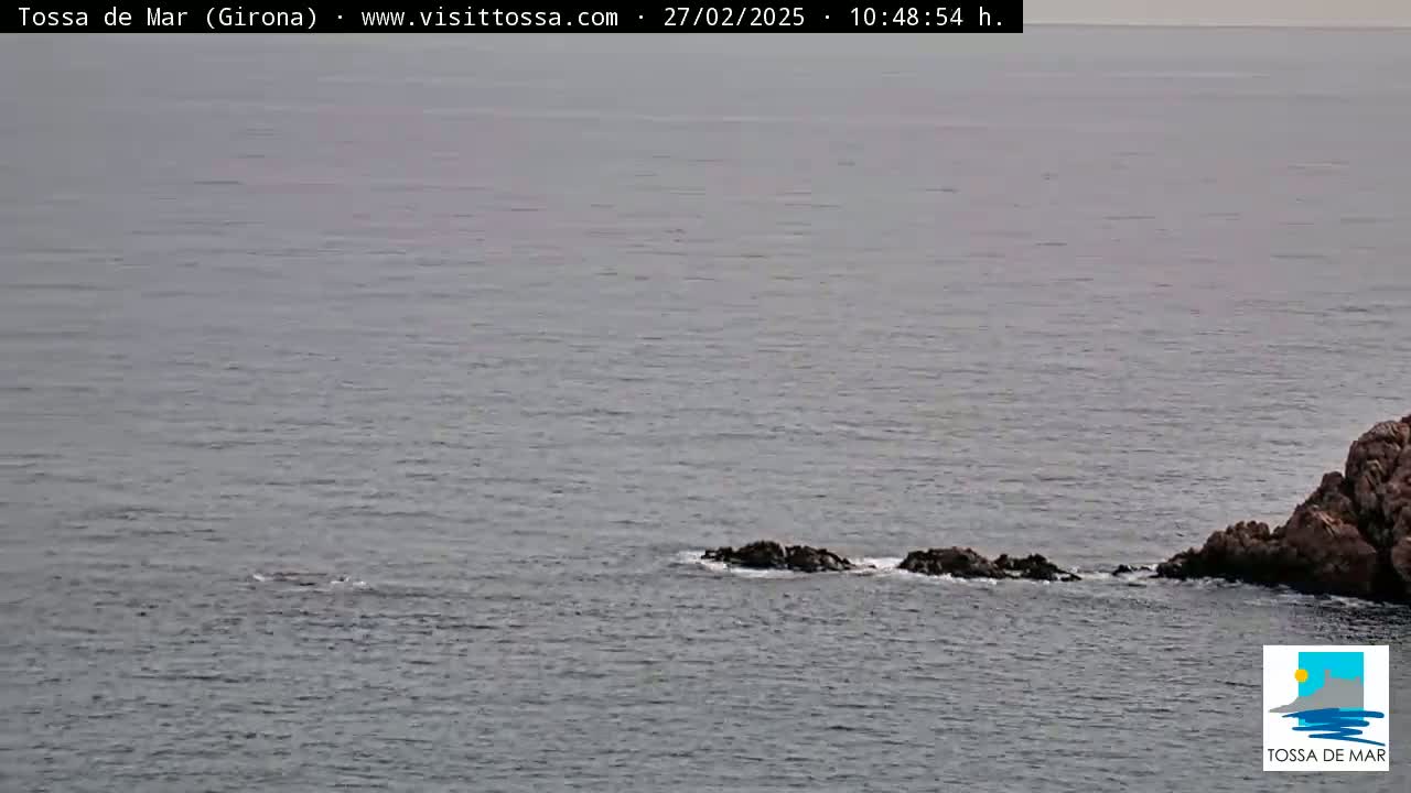A calm, gray sea with a rocky outcrop extends from a larger landmass on the right.