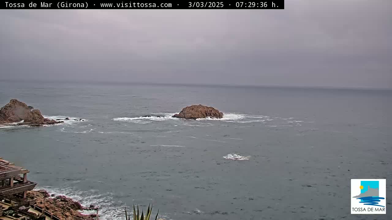 An overcast sky hangs over a rocky coastline and ocean where two small islands are visible.