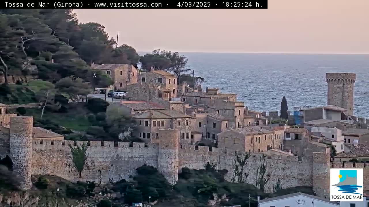 A stone-walled coastal village, under a dusky sky, overlooks a calm sea.
