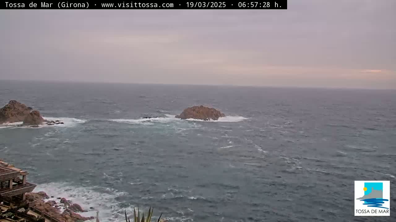 A rocky coastline with choppy grey water under an overcast sky shows two small islands offshore.