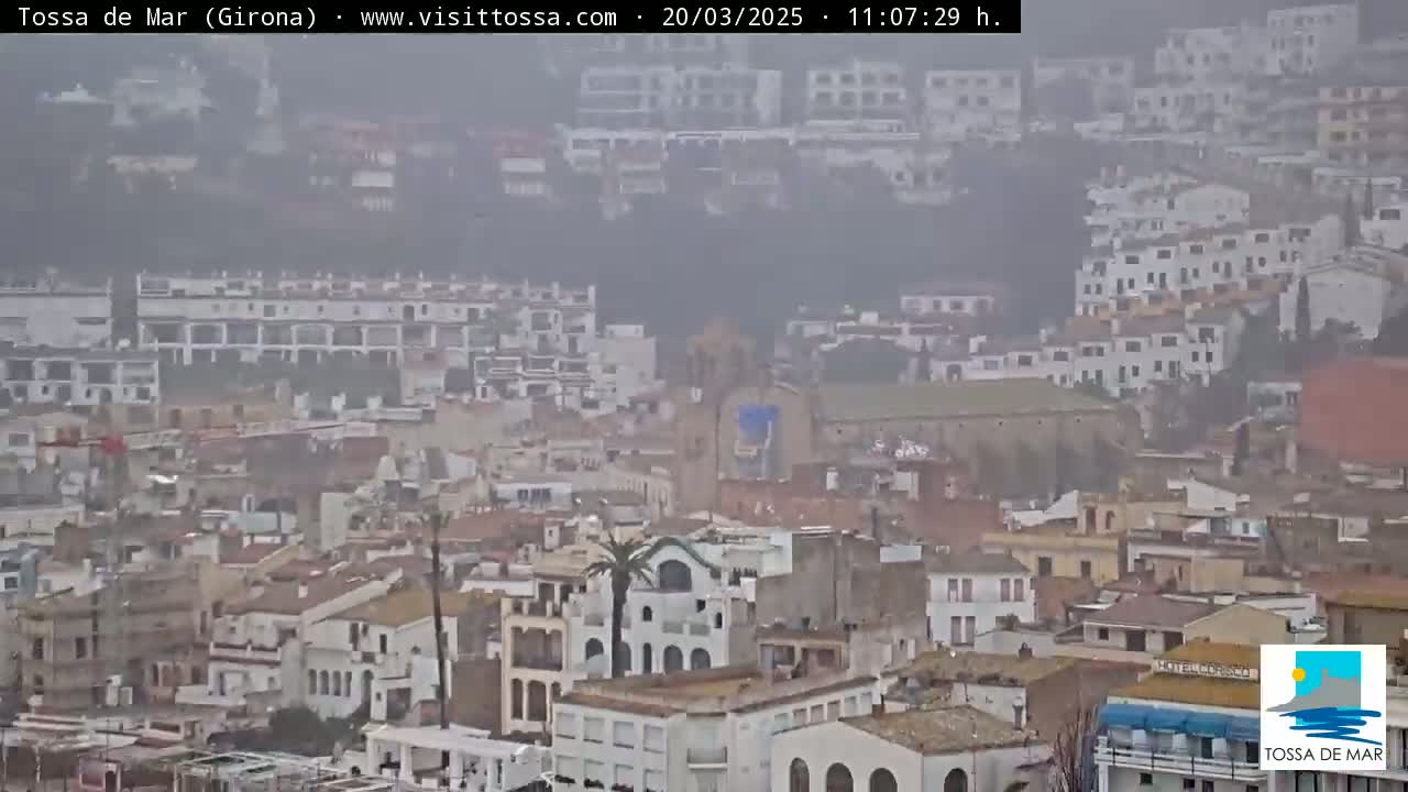 A hazy, overcast view of a coastal town with many closely packed buildings, some appearing whitewashed.