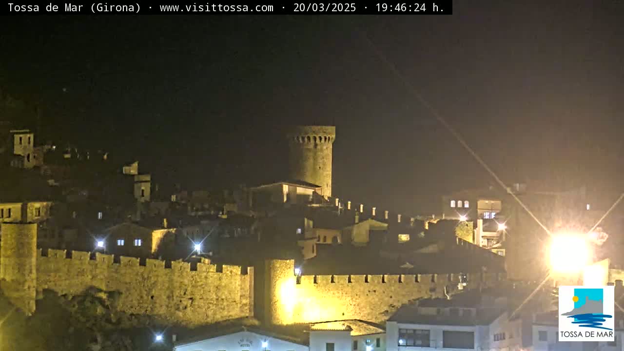 A medieval walled town is illuminated at night.