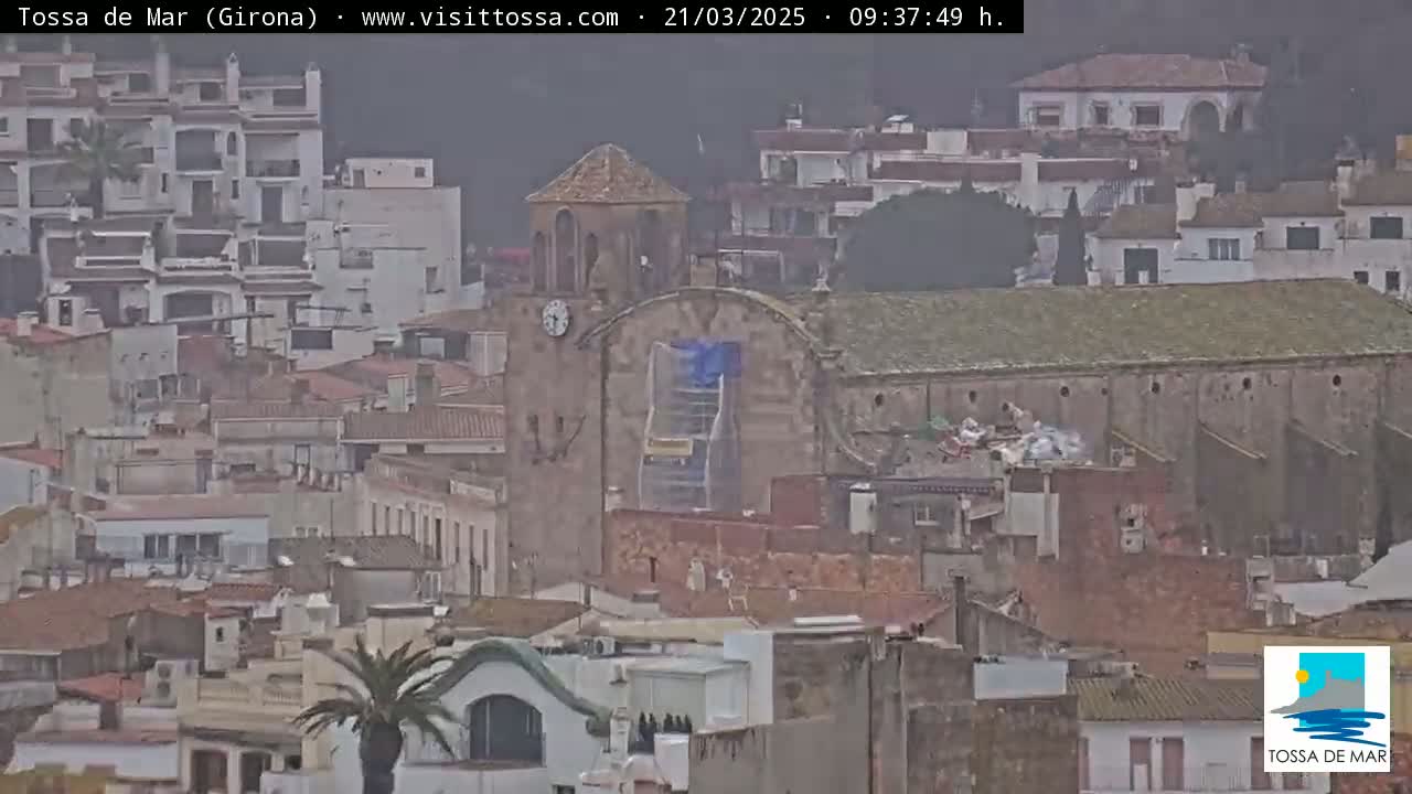 A distant view of a town, showing numerous buildings under an overcast sky, with a church undergoing construction visible in the center.