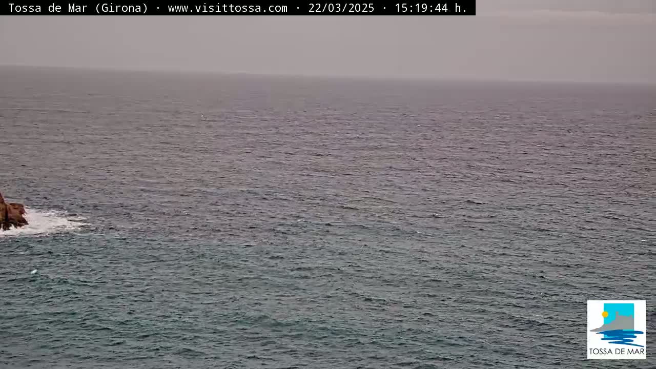 A rocky outcrop juts out into a dark, somewhat choppy sea under an overcast sky.