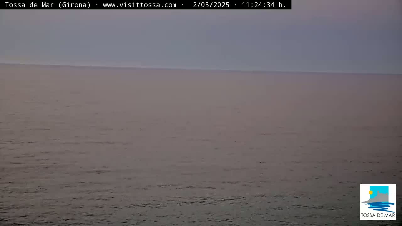 A calm, gray sea is visible under a hazy, overcast sky.