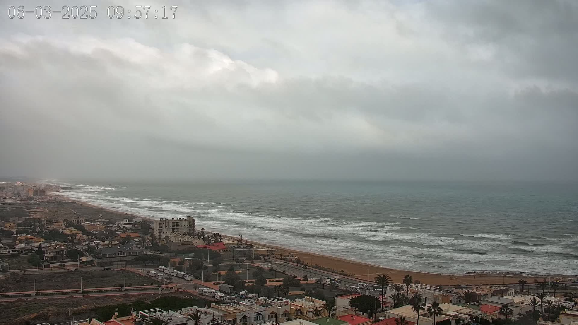 A coastal town with overcast skies and a wavy ocean stretches out to the horizon.
