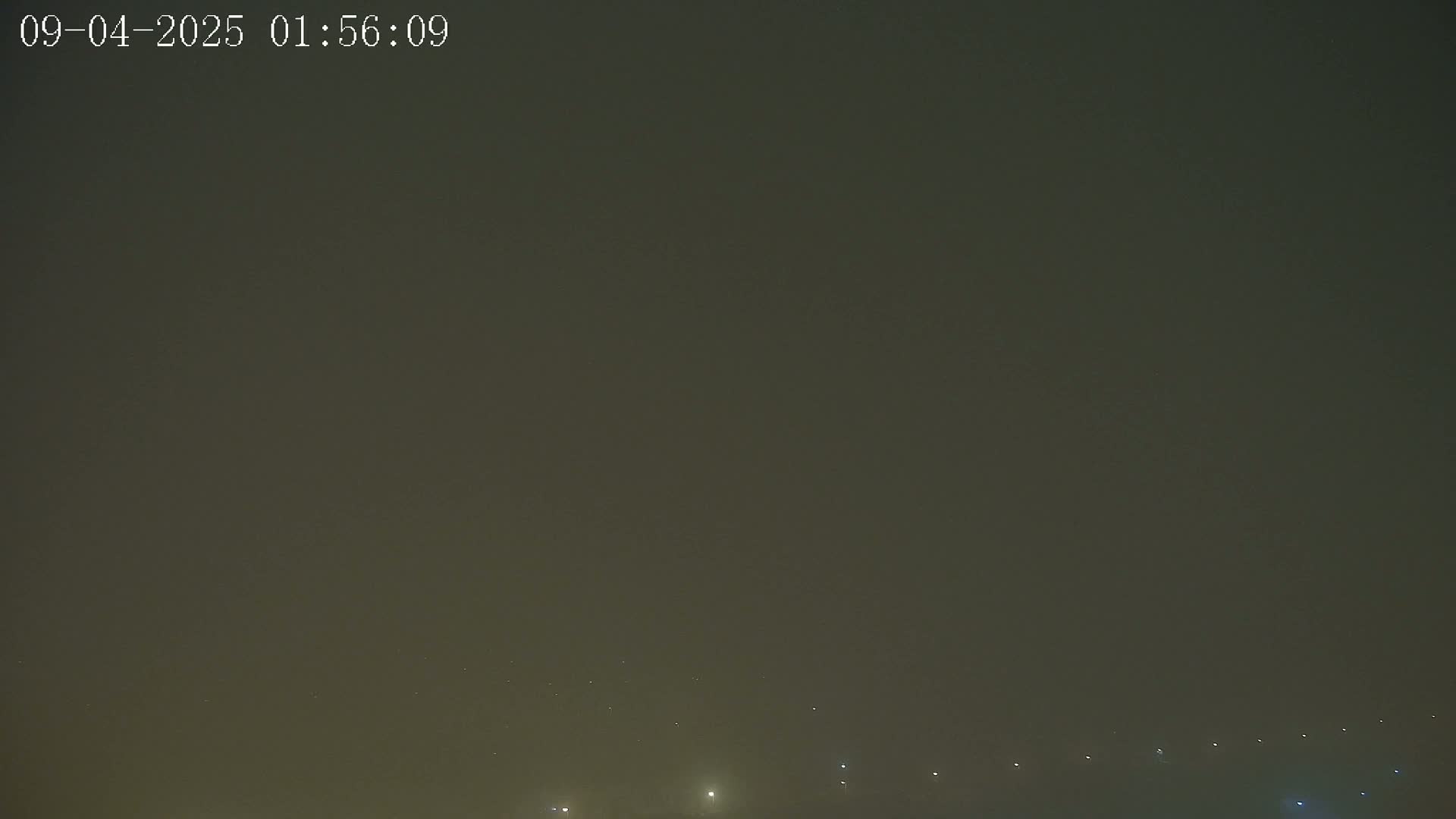 A hazy, dark night sky shows a few faint lights on the horizon.
