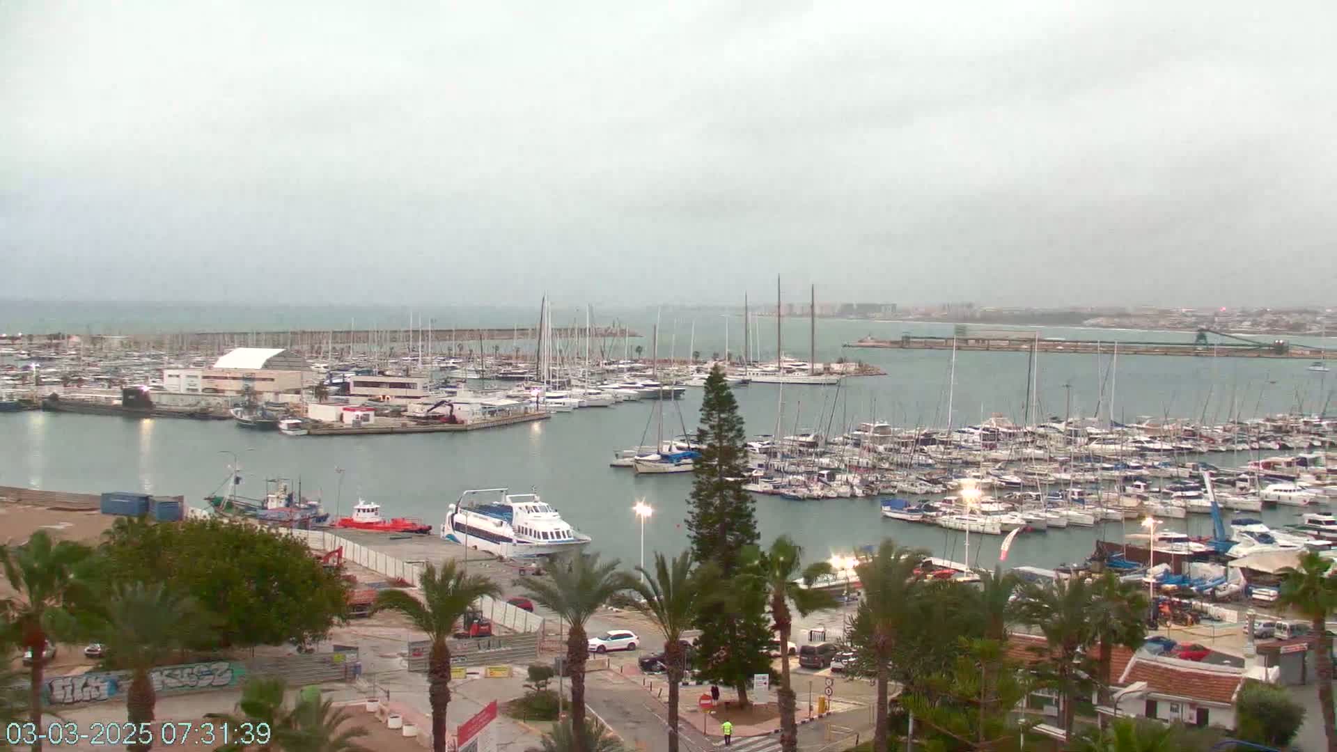 A marina filled with numerous boats and yachts under an overcast sky.