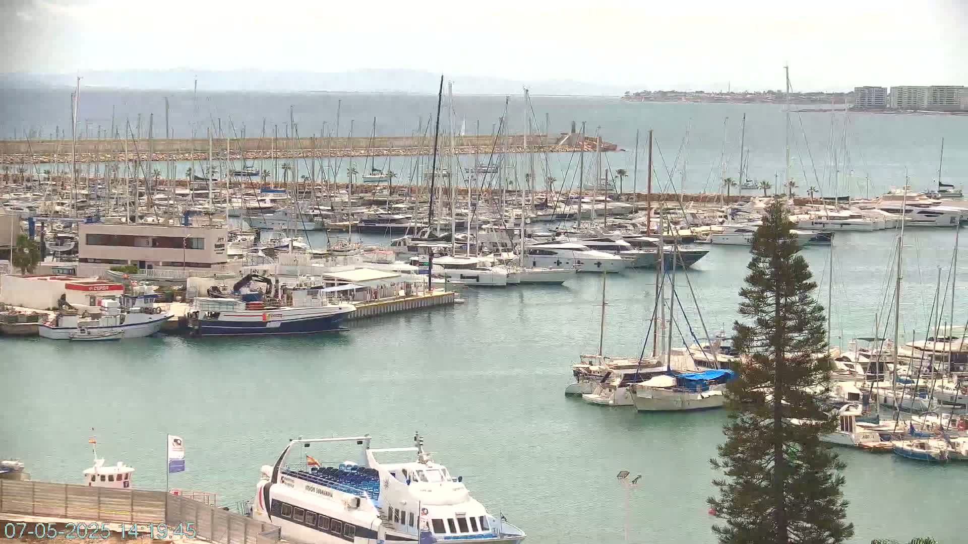 A marina filled with numerous sailboats and motorboats on a calm, overcast day.