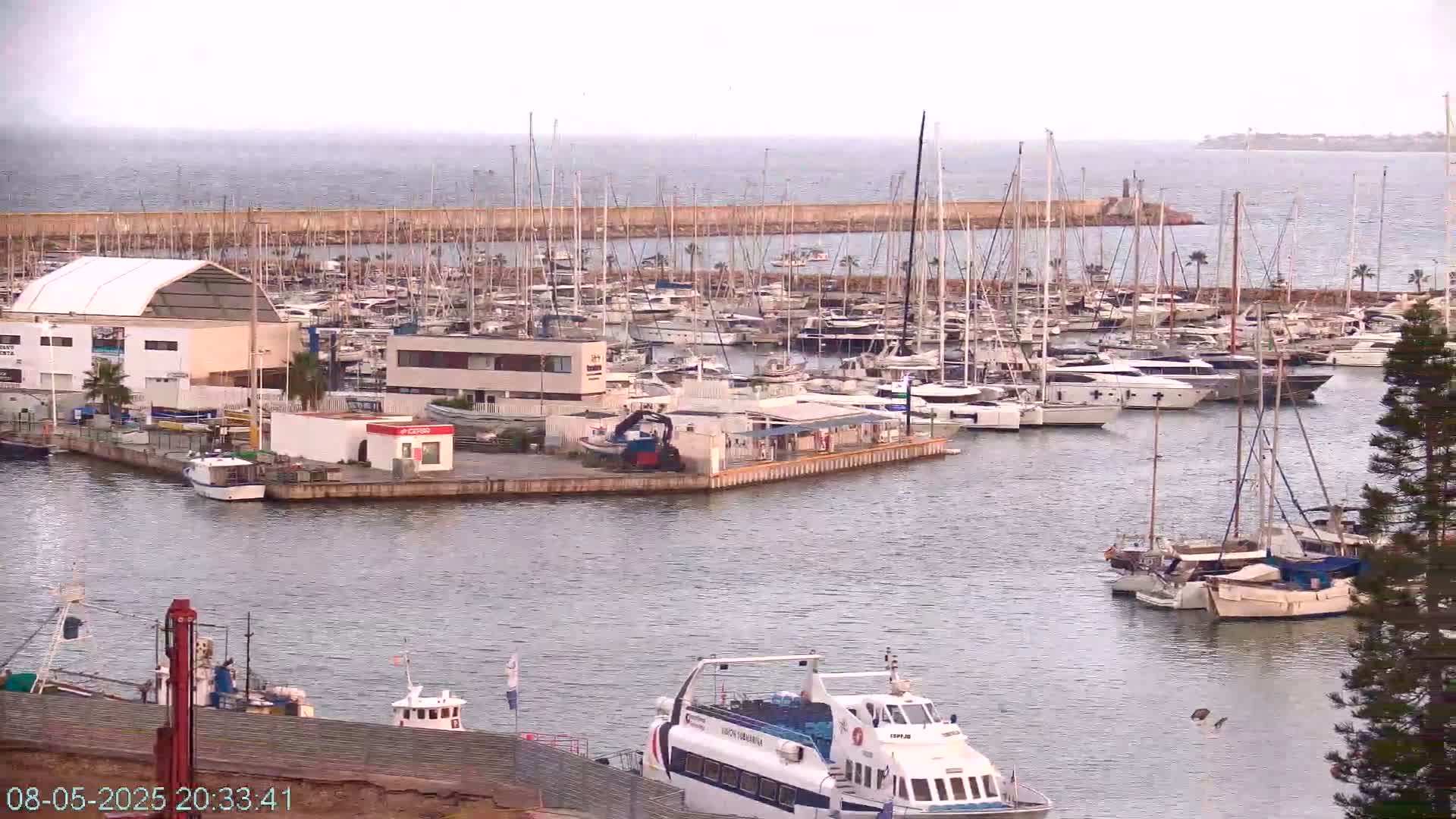 A marina filled with numerous sailboats and motorboats under an overcast sky.