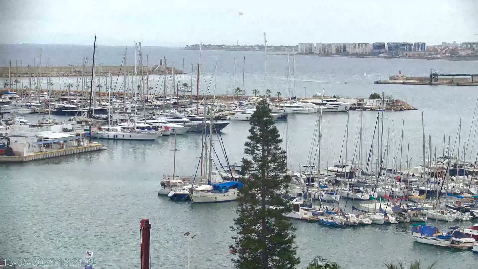 A marina filled with numerous sailboats and motor yachts on a cloudy day.