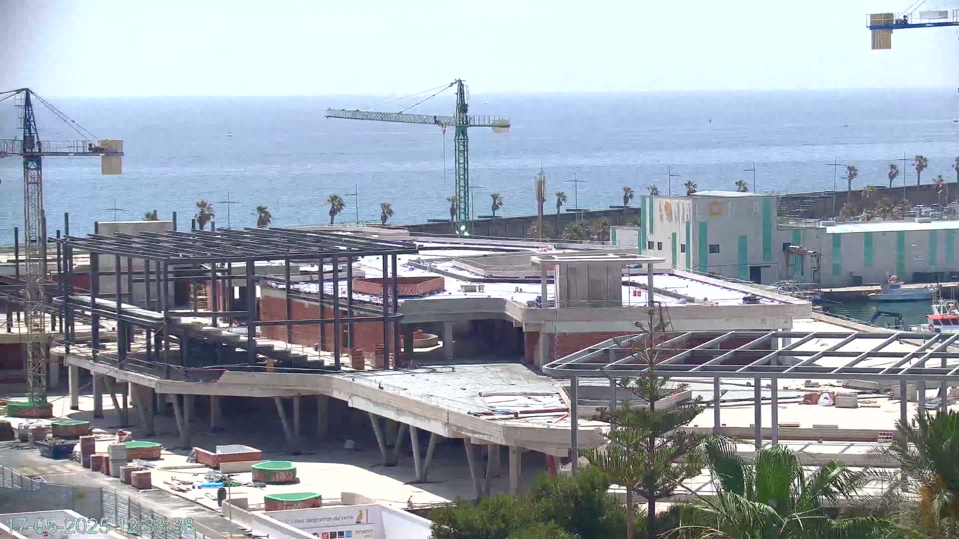 A large building under construction near a calm ocean under a sunny sky.