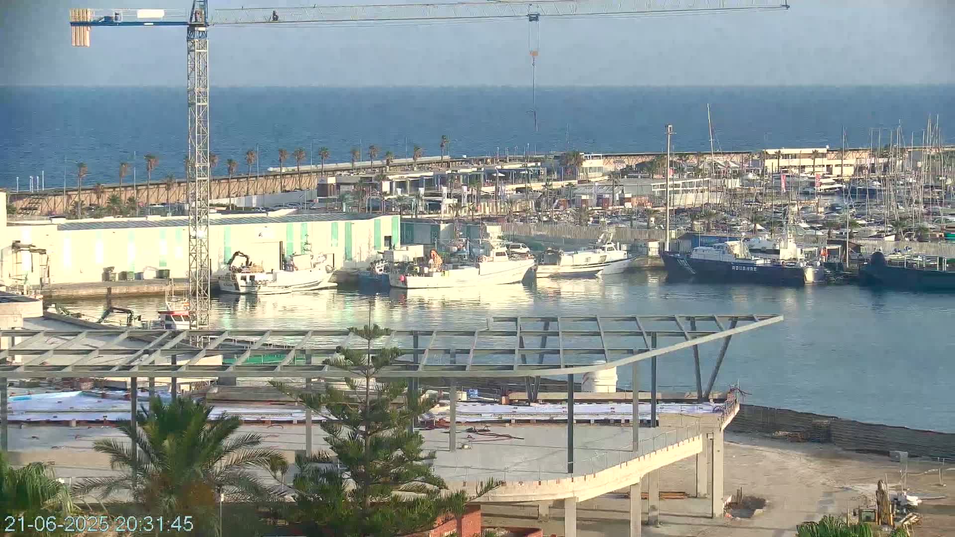 A harbor with numerous boats and a construction site under a clear sky.