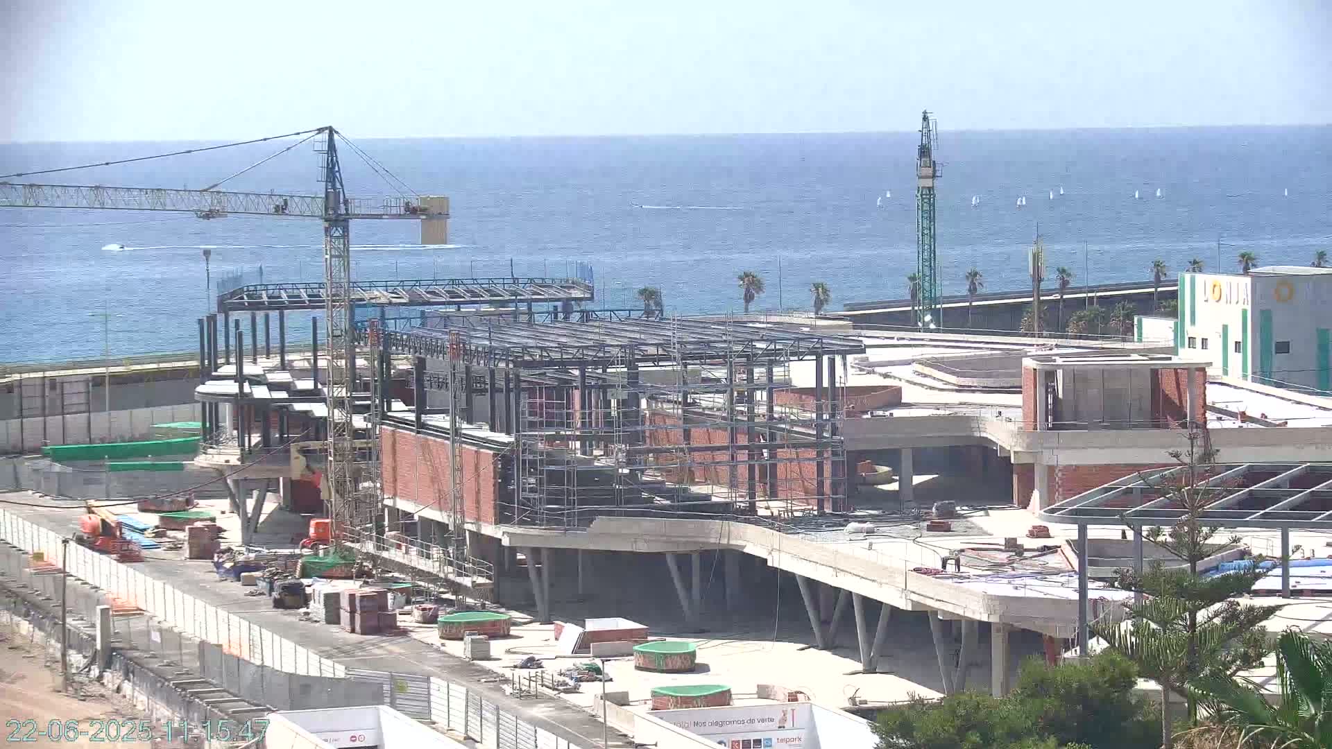 A large building under construction near a body of water on a sunny day.