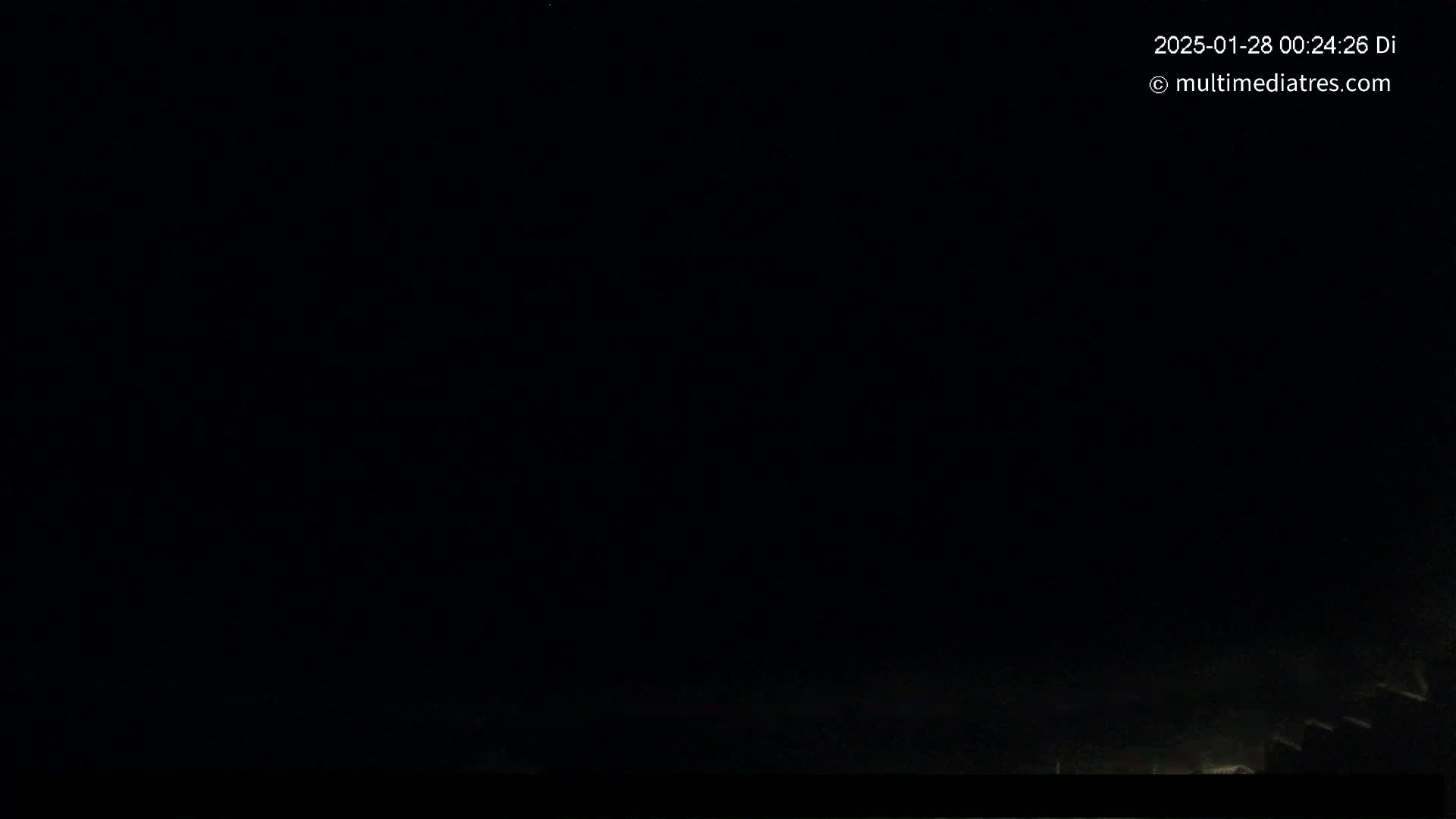 The image shows a very dark, nighttime scene with a few faint lights visible near the bottom.