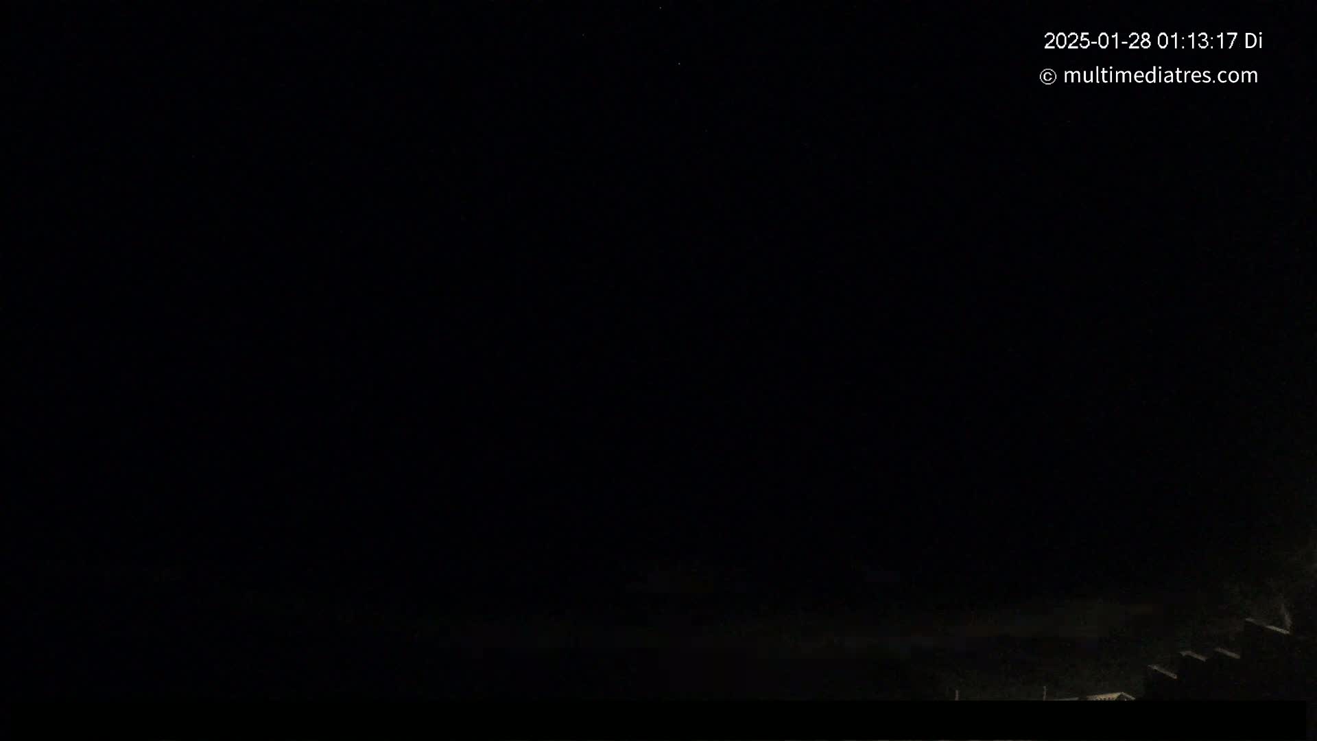 A very dark nighttime scene shows a hint of a light horizon line with some dark shapes at the very bottom.