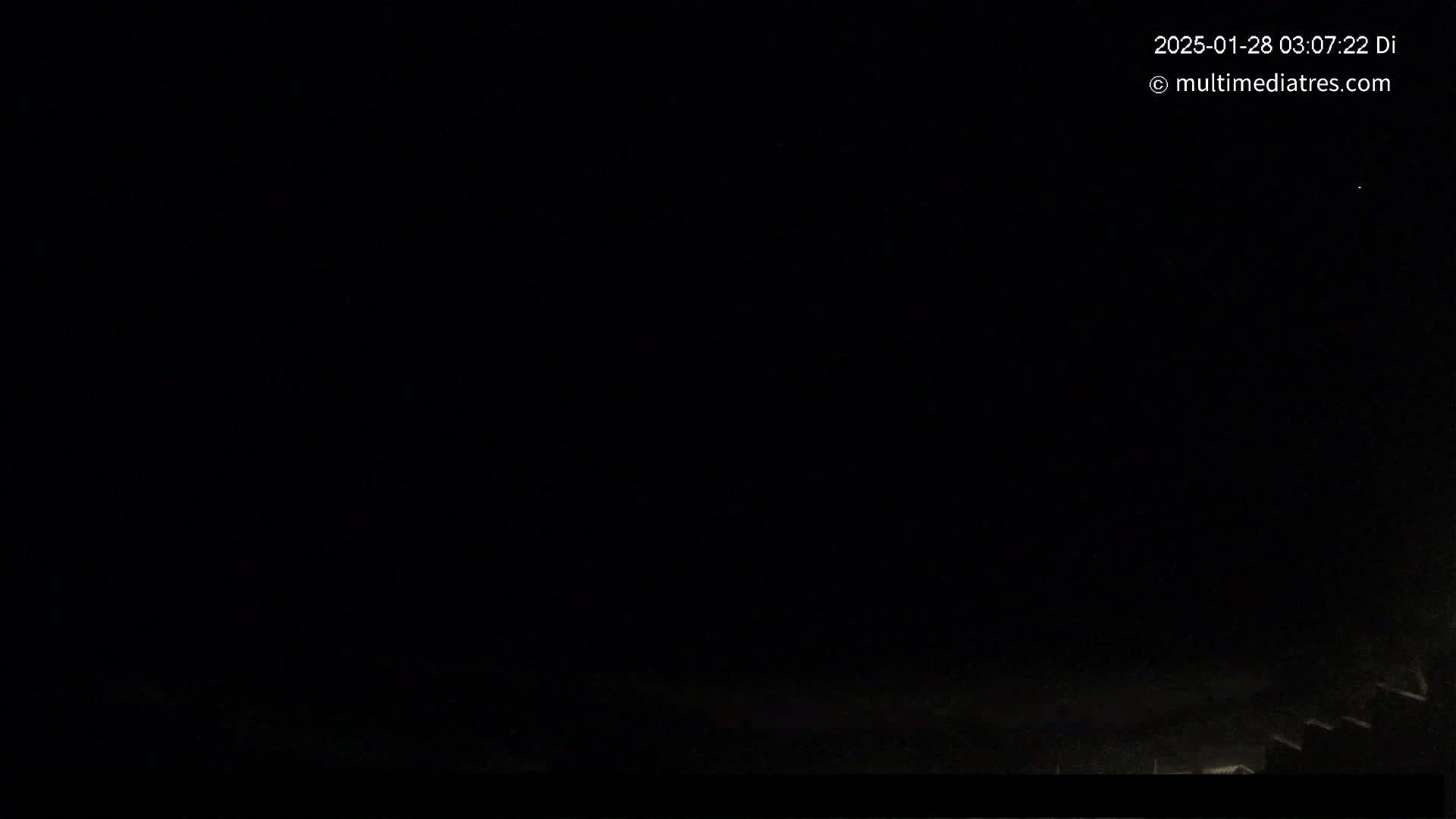 A nighttime, dark outdoor scene shows a very faint light near the horizon.