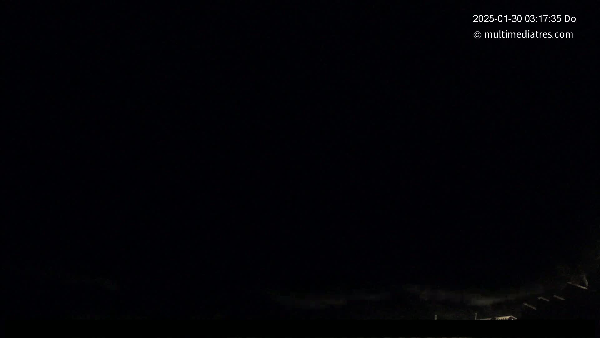 A nighttime scene shows a dark sky with a few faint lights visible at the very bottom of the frame.