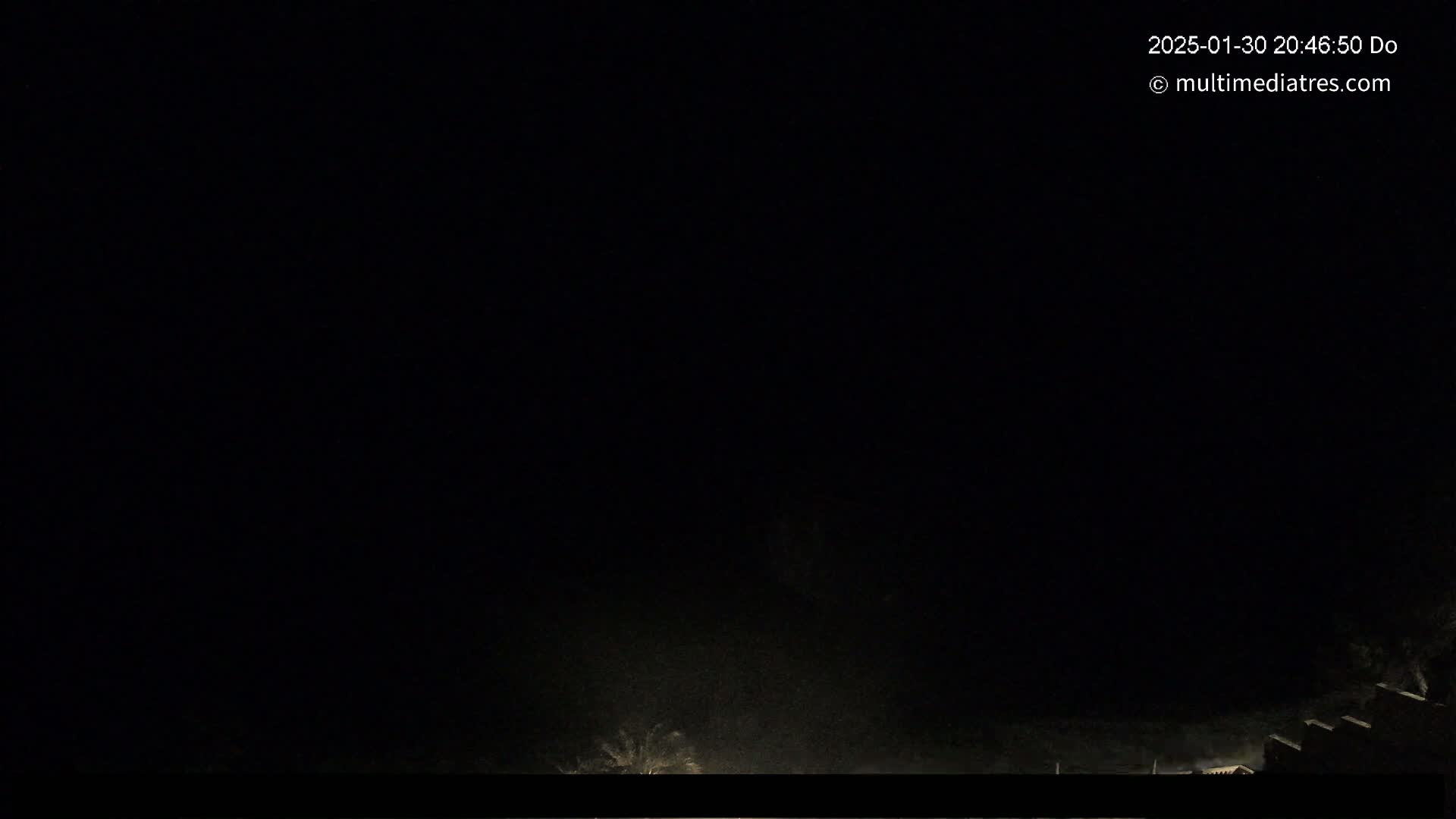 A dark, nighttime scene shows a low horizon with indistinct features, under a completely overcast sky.