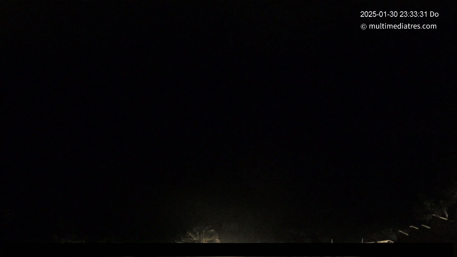 A nighttime outdoor scene shows a very dark sky and faint illumination near the bottom of the frame.