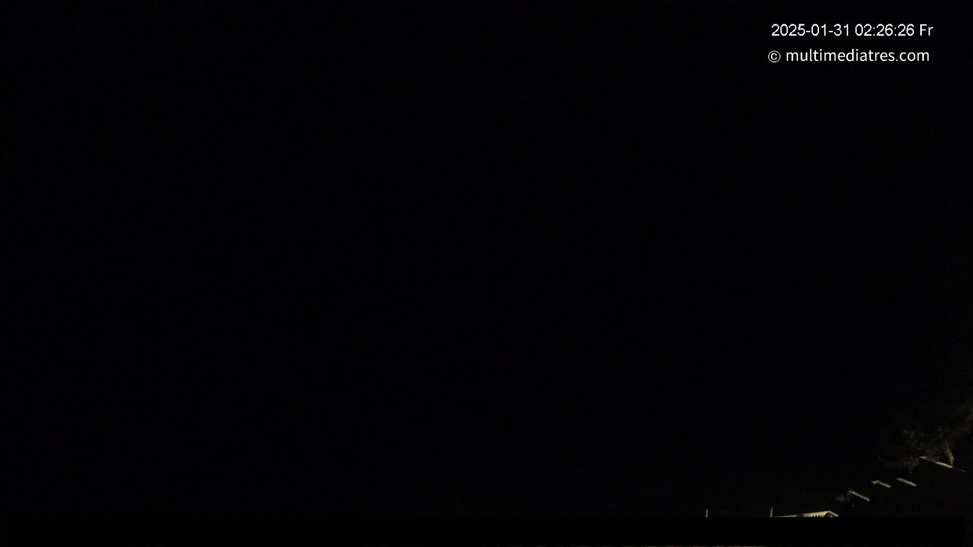 A nighttime outdoor scene shows a dark sky and faintly illuminated rooftops at the bottom of the image.