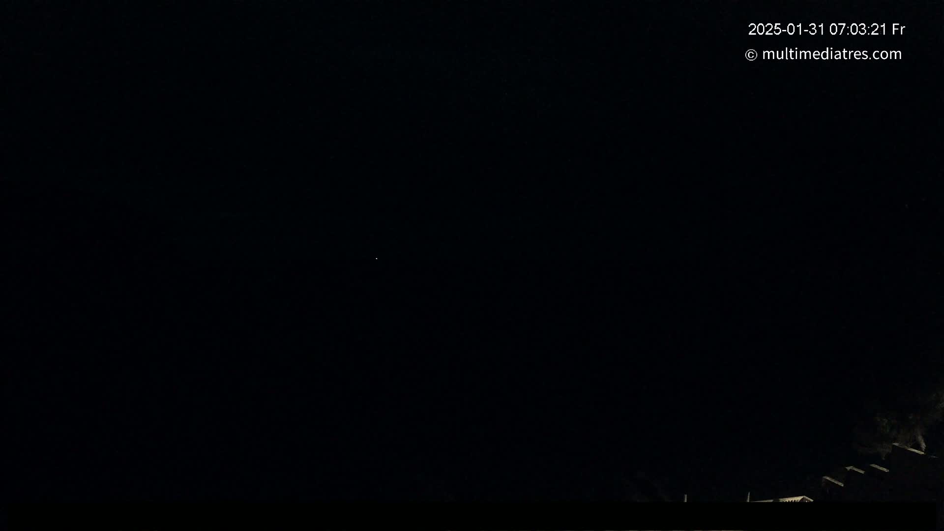 A dark nighttime scene shows a very faint light in the distance and a slightly brighter area at the very bottom of the frame.