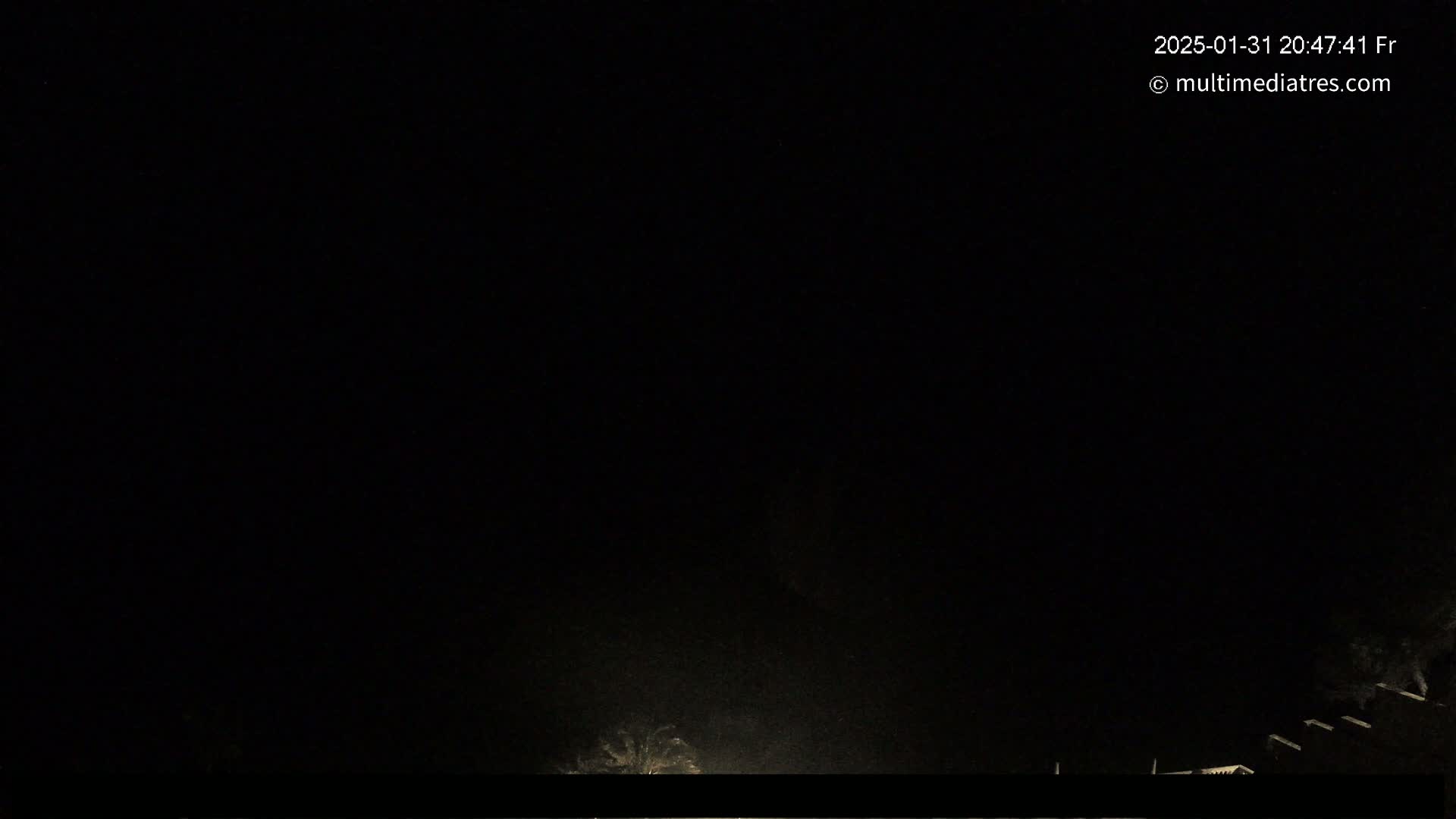 A nighttime outdoor scene shows a dark sky and faintly illuminated objects at the bottom of the frame.