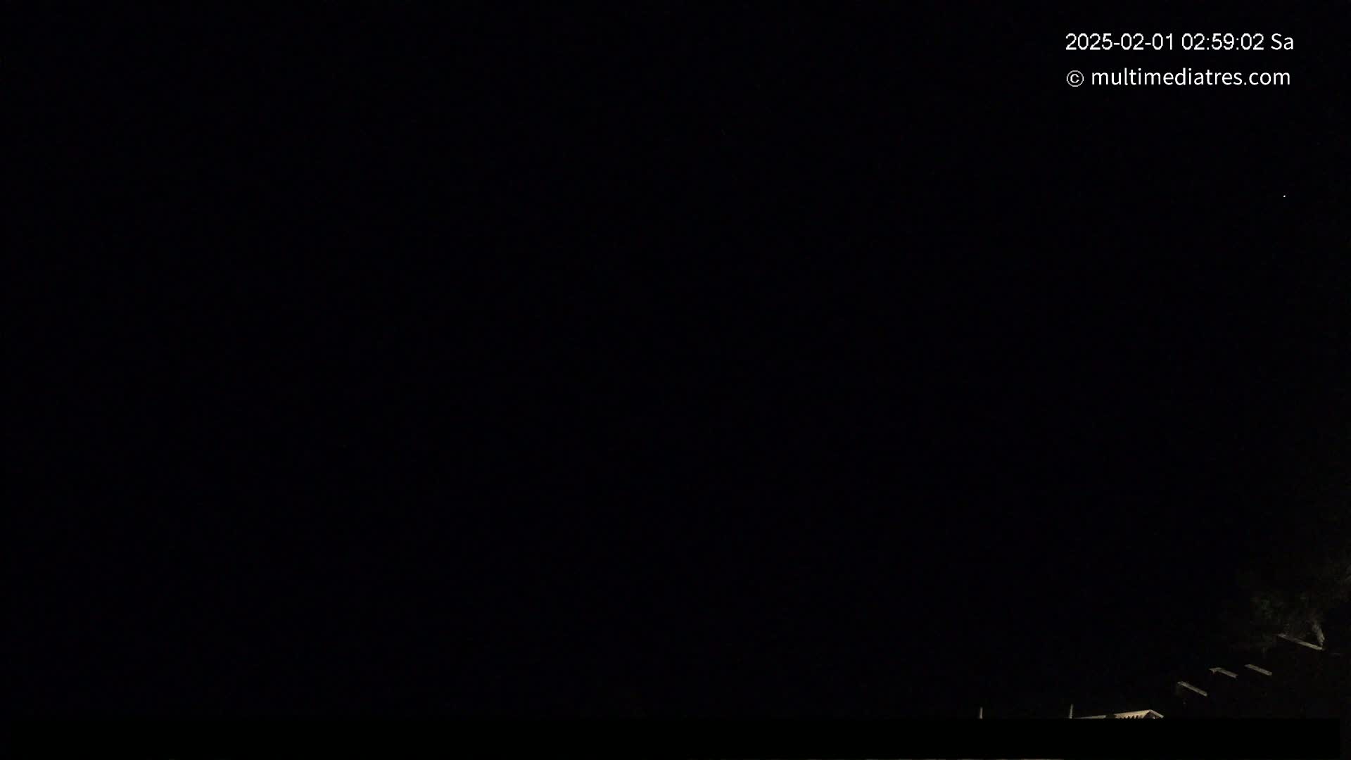 A nighttime outdoor scene shows a dark sky and a portion of a dark structure at the bottom of the image.