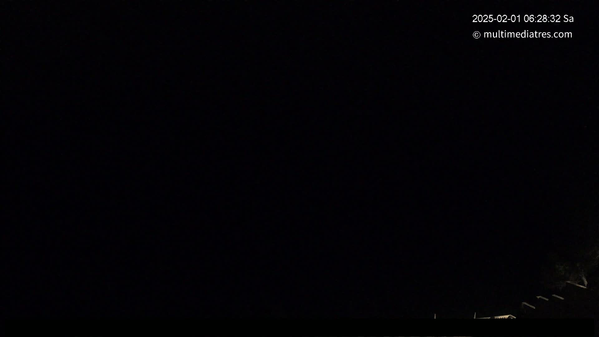 A nighttime outdoor scene shows a mostly dark sky with a few dimly lit structures visible at the bottom.