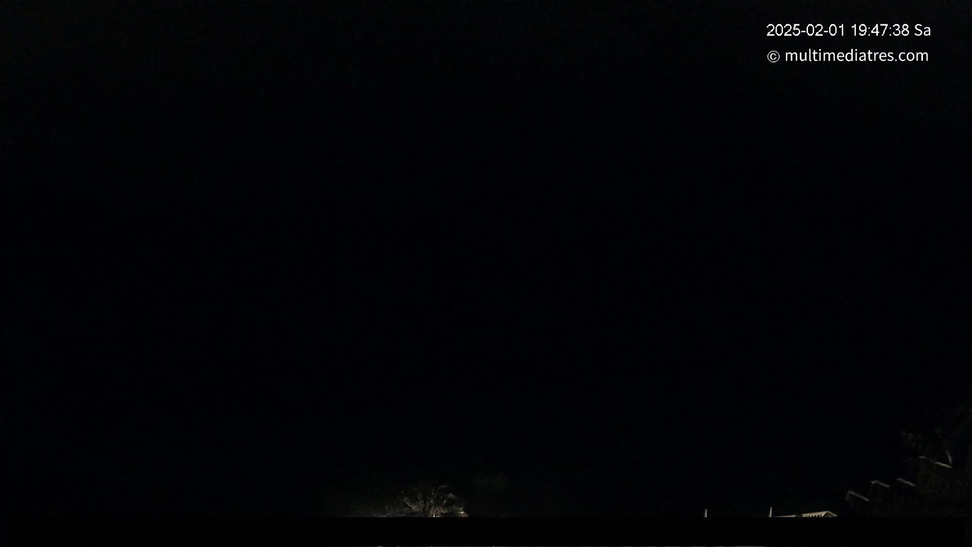 The image shows a nighttime outdoor scene with a dark sky and faintly visible structures in the bottom edge of the frame.