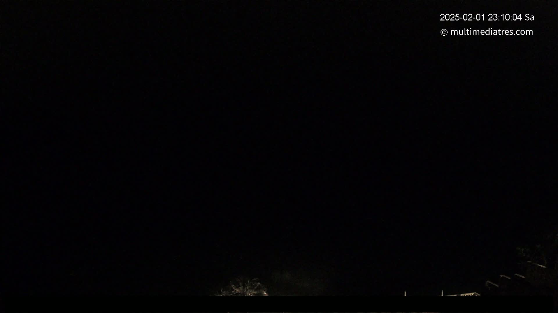 A mostly dark nighttime scene shows a hint of faint light at the bottom, possibly from distant buildings or lights, under a completely dark sky.