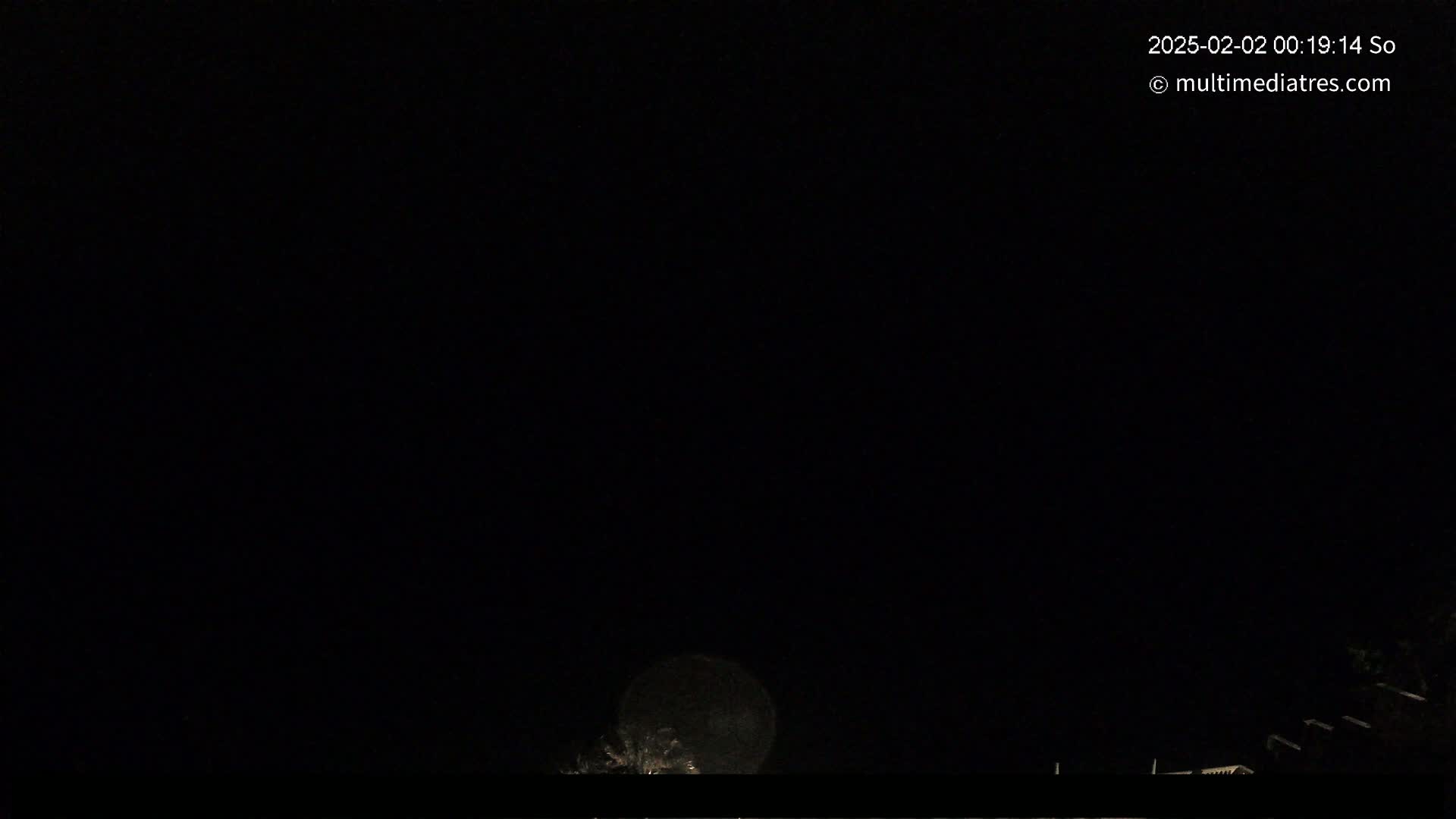 A bright, full moon is visible in the night sky above a dark, low-lying landscape.
