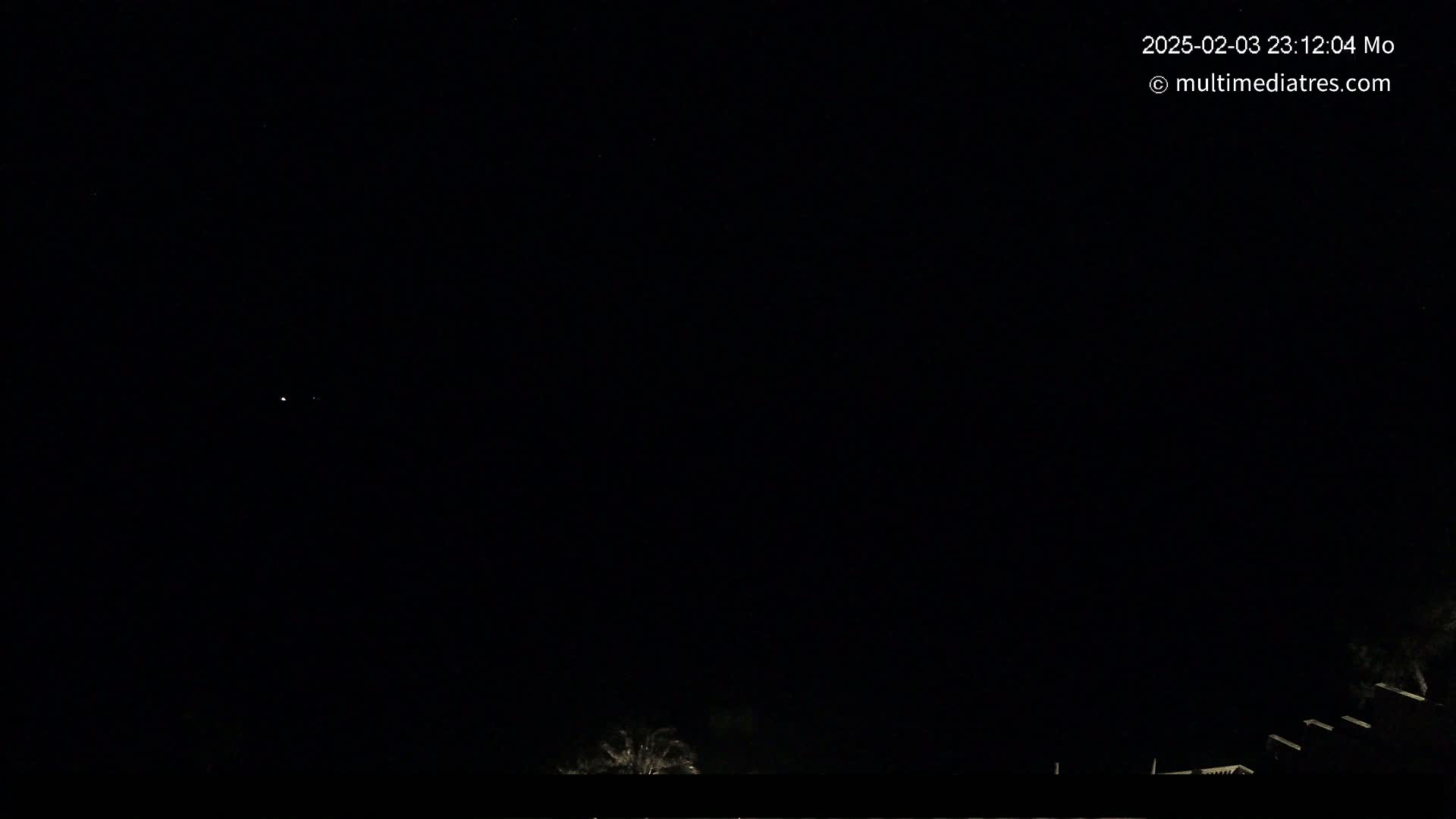 A dark night sky with a few faint stars and a dimly lit landscape at the bottom.