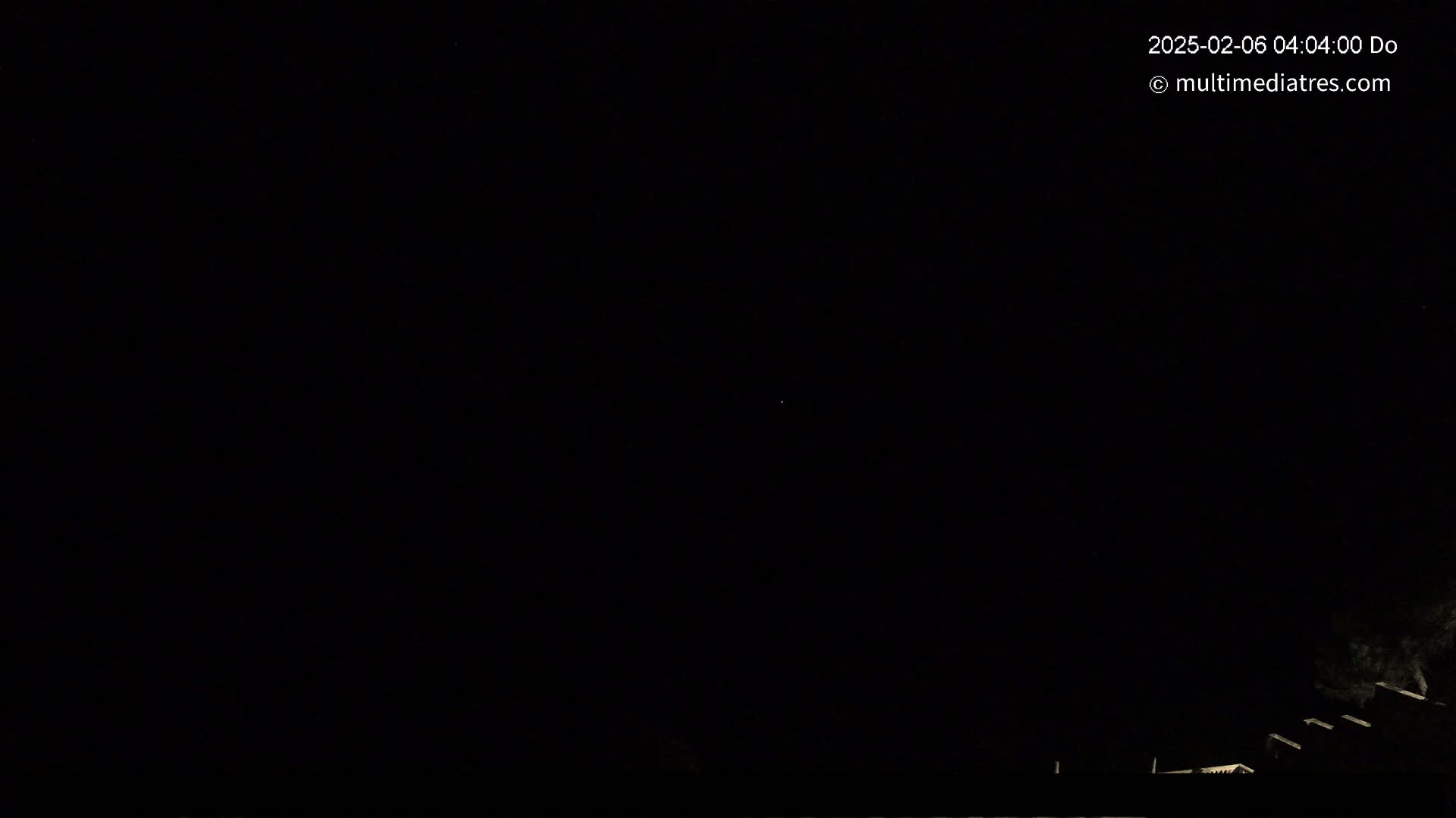 A nighttime outdoor scene shows a dark sky with a few faintly visible stars above a dark silhouette of buildings or structures at the bottom.