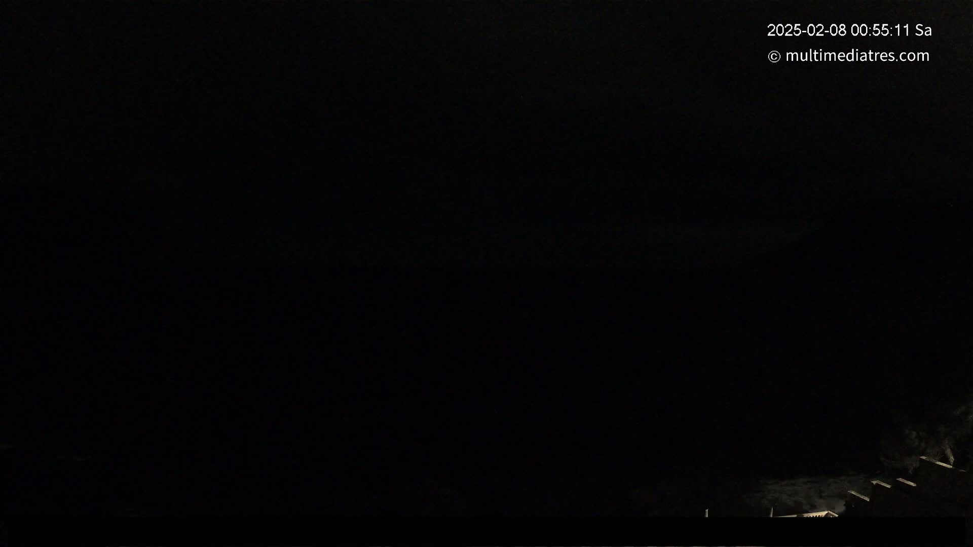 A nighttime, dark scene shows a few faint lights at the very bottom of the frame.