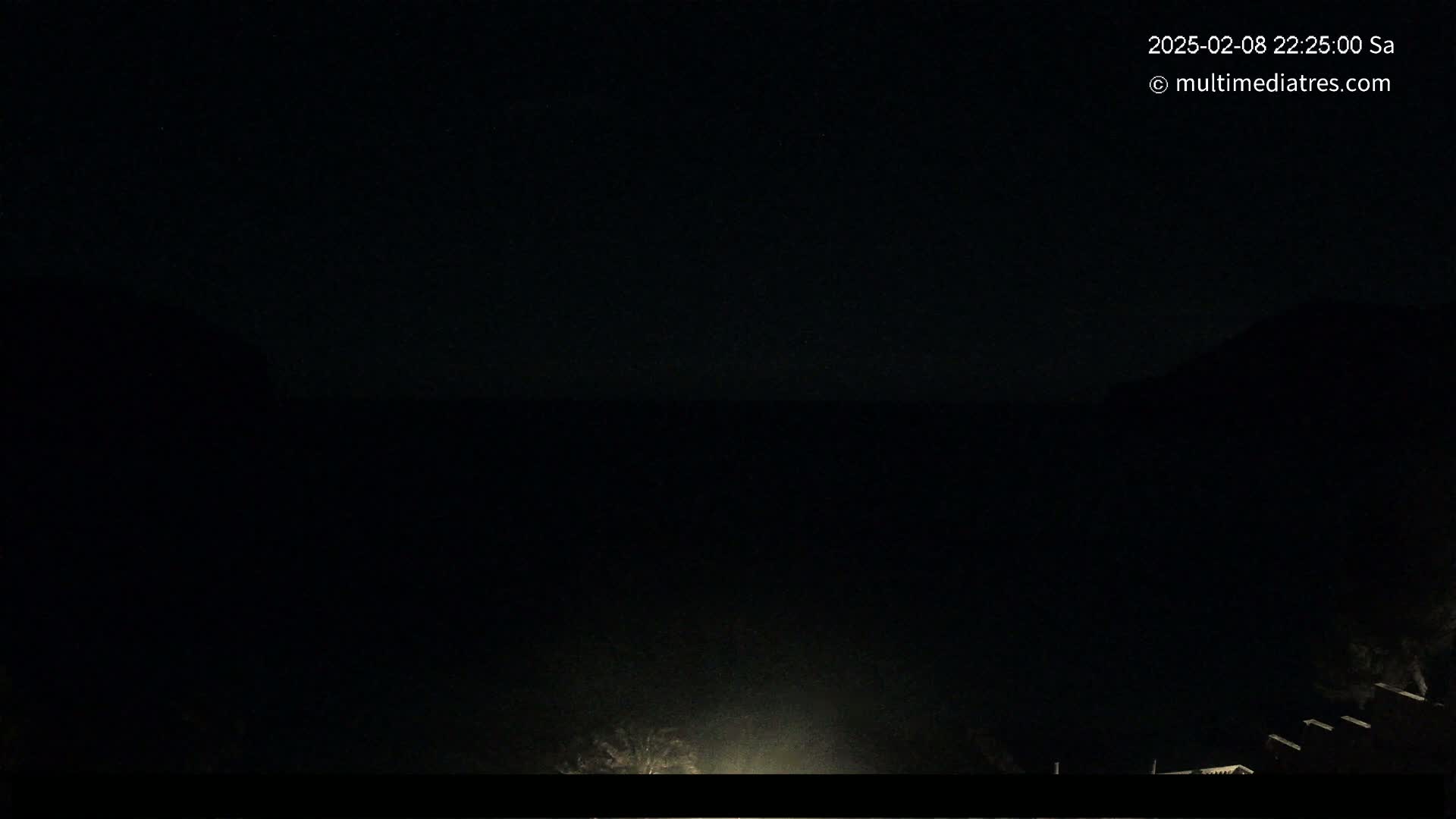A dark nighttime scene shows a mostly obscured landscape with a hint of light near the bottom.