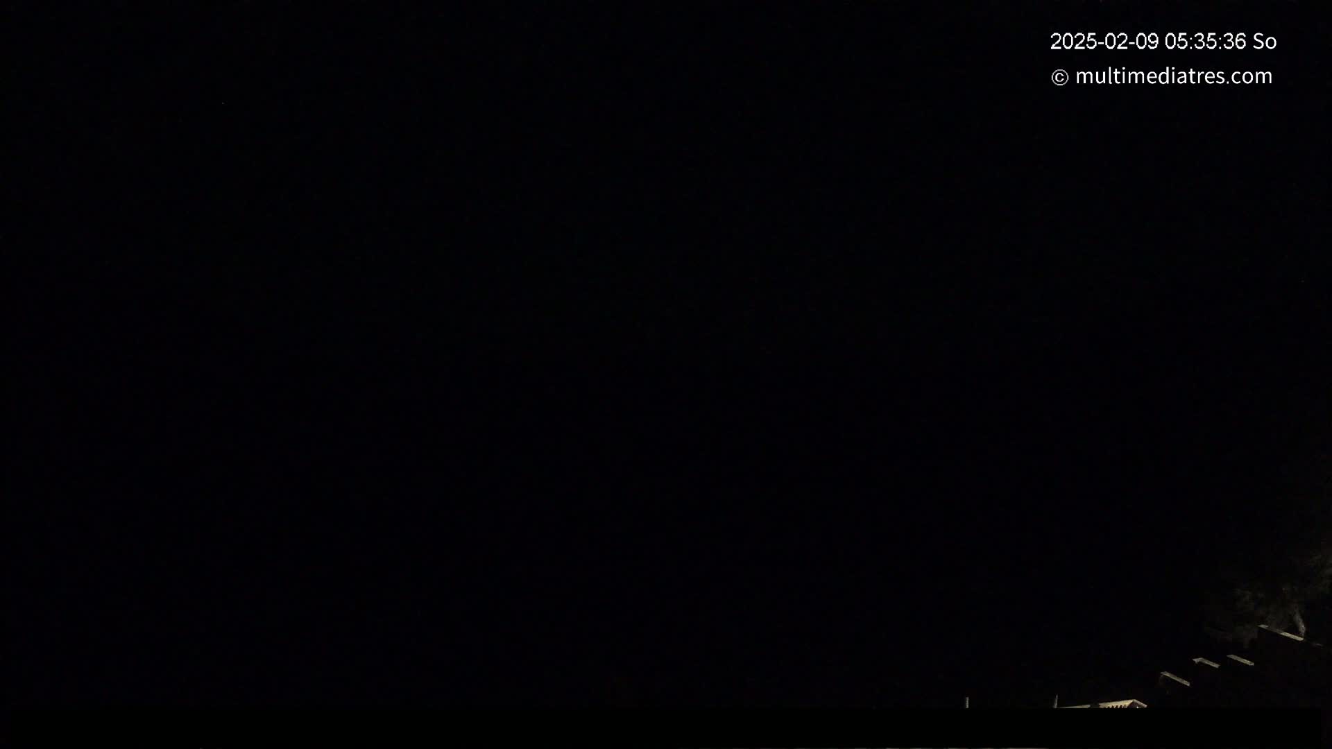 A nighttime outdoor scene shows a dark sky with faint light at the bottom edge.