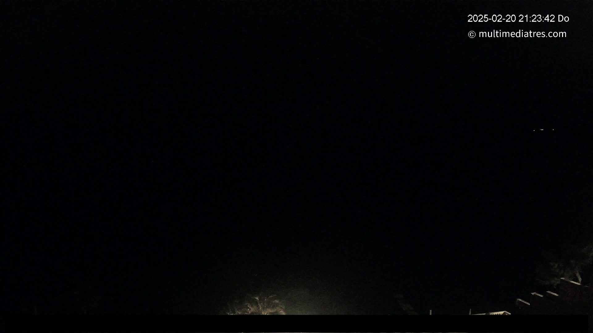 A nighttime outdoor scene shows a dark sky and the faint illumination of a structure at the bottom of the frame.